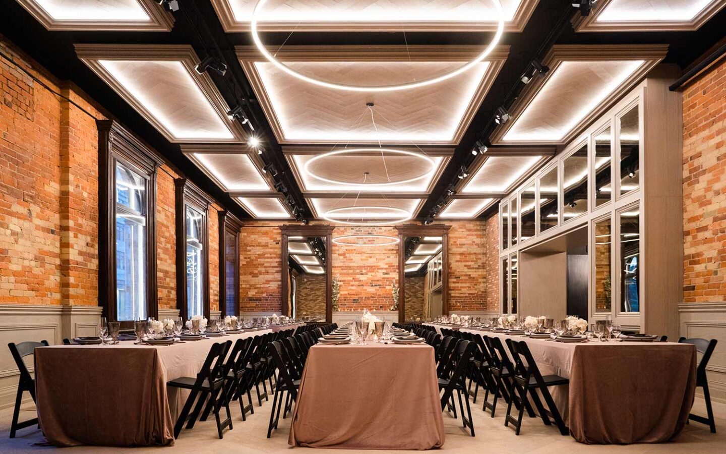 wedding venue with long rectangular tables and high brick walls with approximately 150 seats