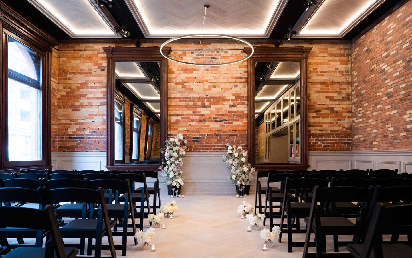 wedding venue with two large mirrors, two flower arrangements, and seats for about 70 people