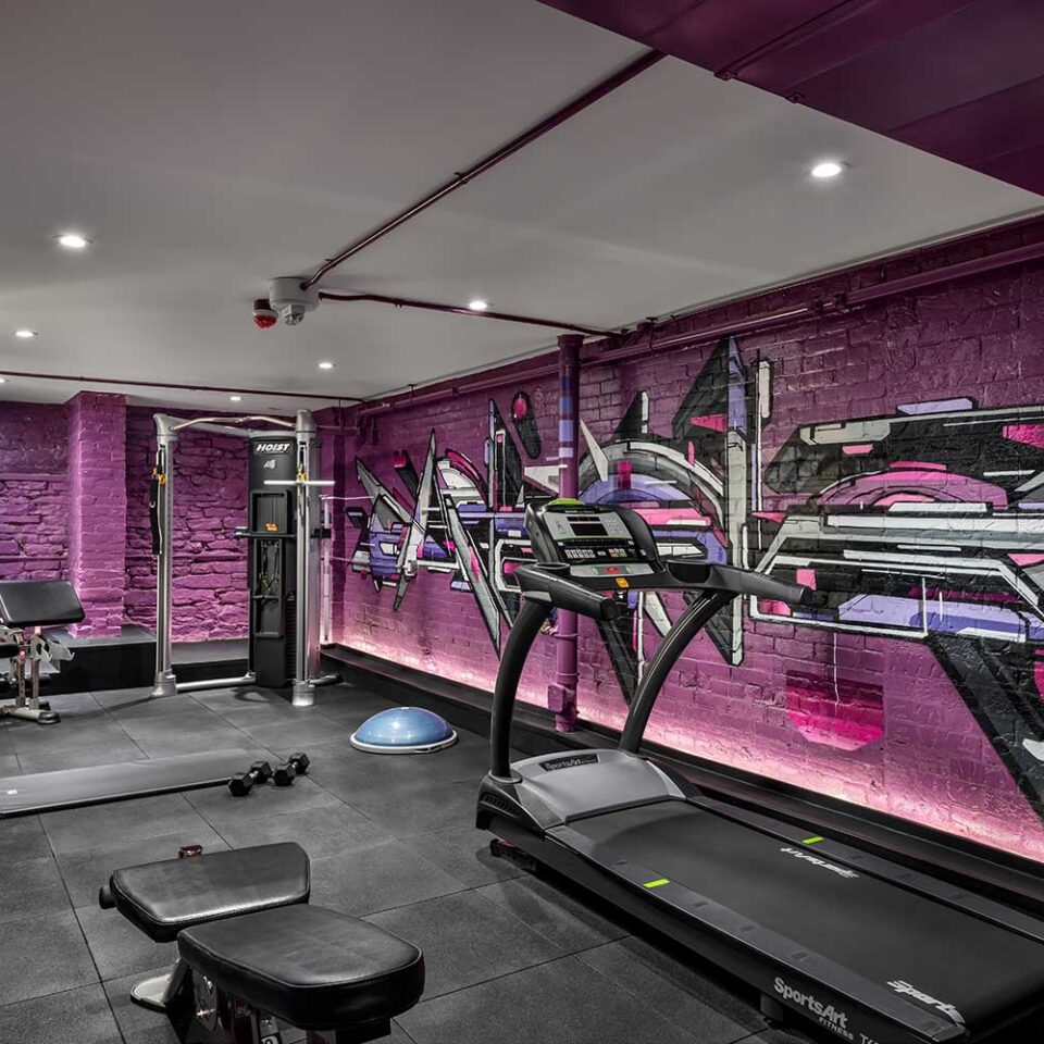 photo of a gym with graffiti brick walls and gym equipment