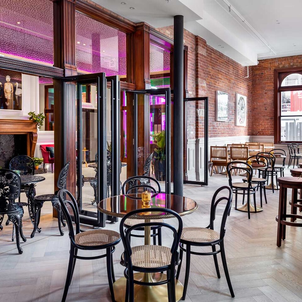 rendering of a cafe with a wooden bar, small tables, and brick interior wall