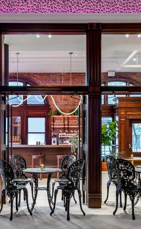 rendering of a cafe with a wooden bar, small tables, and brick interior wall