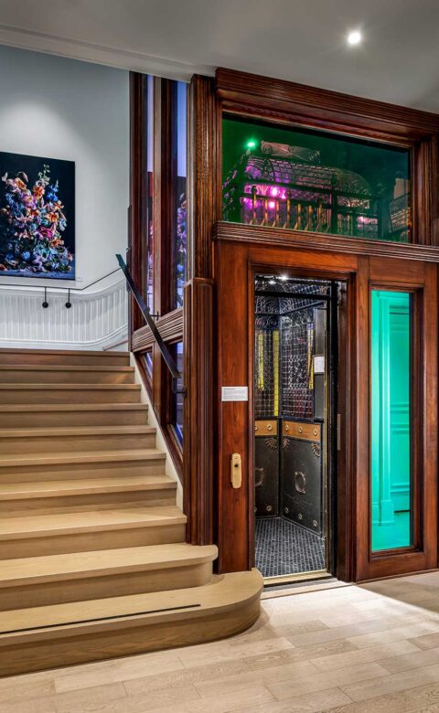 staircase next to a vintage elevator with a gated door