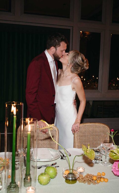 bride and groom kissing standing behind table
