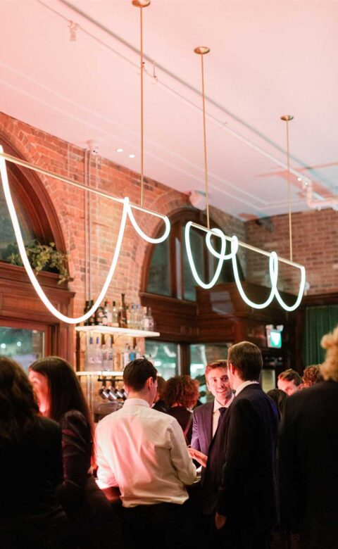 people standing in front of bar talking with lighting hanging overhead