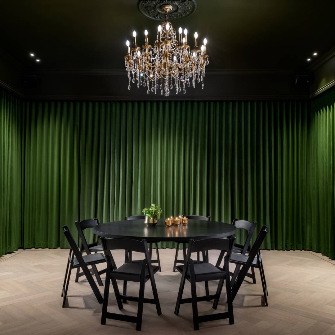 room enclosed with green curtains and tables and chairs in the middle